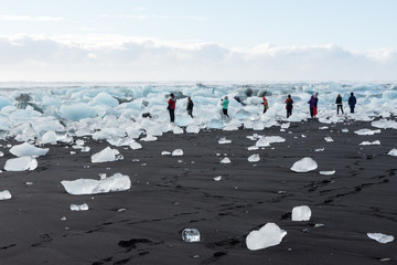 View of the tourists photographing ice floes in the beach in Jökulsárlón, Icelands