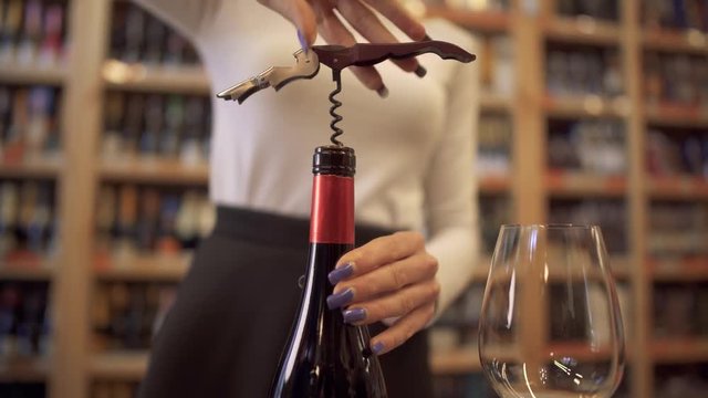 Female hands uncorking a bottle of wine close-up. Girl uncorking the wine with a corkscrew.