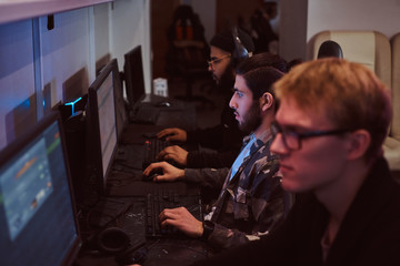 Team of teenage gamers plays in a multiplayer video game on pc in a gaming club.