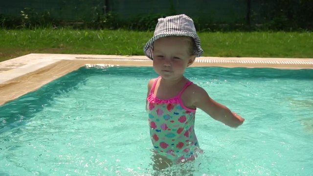 Girl splashing in swimming pool in slow motion