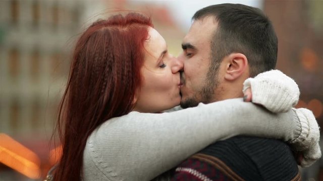 Young Happy Attractive Amorous Couple Embracing And Kissing Outdoor. Merry Christmas and New Year Concept. Good Mood and Having Fun Together.