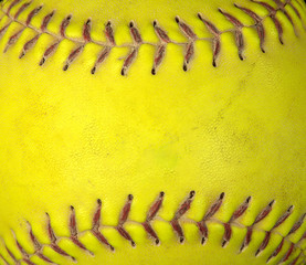 extreme close up of used neon yellow soft ball with red stitched seams