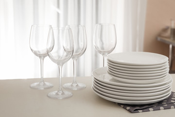 Stack of clean dishes and glasses on table in kitchen