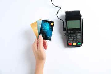 Woman with credit cards and modern payment terminal on white background, top view