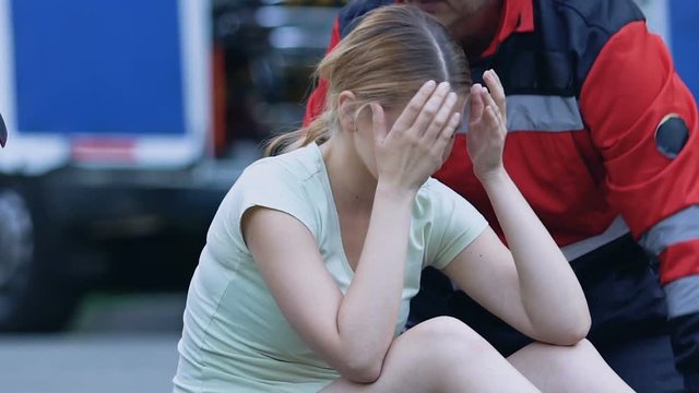 Girl feeling attack of headache and dizziness ambulance team rendering first aid