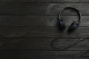 Fototapeta na wymiar Stylish modern headphones and space for text on wooden background, top view