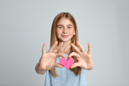Pretty teenage girl with decorative heart on color background