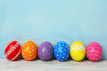 Decorated Easter eggs on table near color wall. Space for text