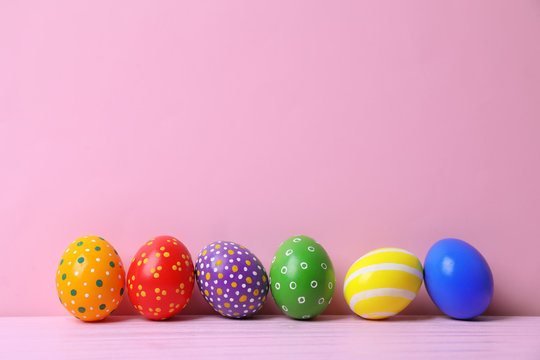 Decorated Easter eggs on table near color wall. Space for text