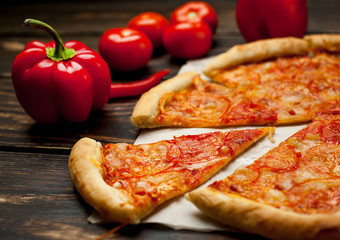 pizza on a wooden table with ingredients, tomato, pepper, sunflower oil