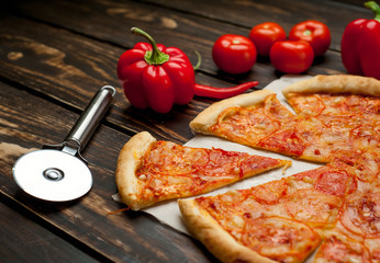 pizza on a wooden table with ingredients, tomato, pepper, sunflower oil