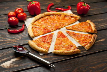 pizza on a wooden table with ingredients, tomato, pepper, sunflower oil
