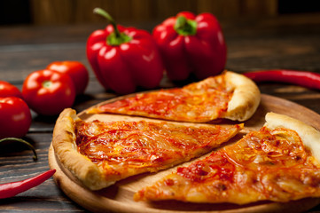 pizza on a wooden table with ingredients, tomato, pepper, sunflower oil