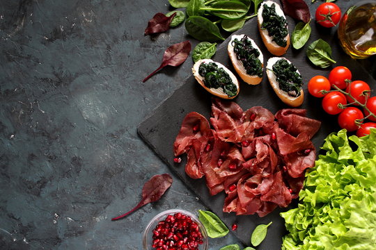 Healthy diet food concept. The bruschetti with spinach, bresaola and pomegranate. Diet food. Top view with copy space.