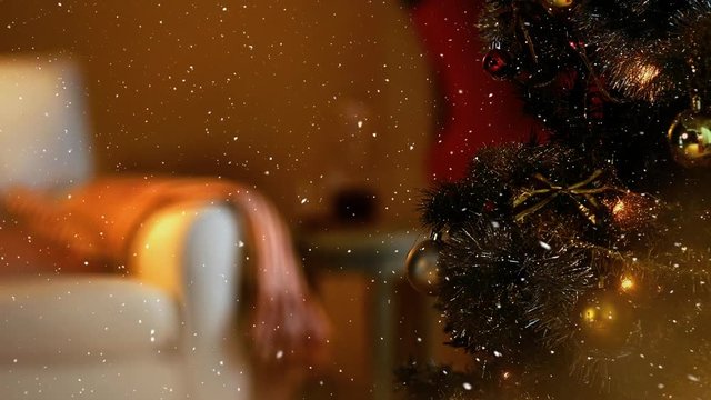 Video composition with falling snow over blurry video of Christmas tree lights in cozy room