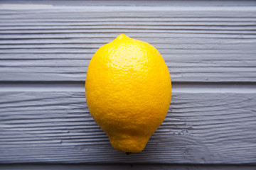 Whole and cut lemons on grey wooden surface