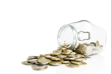 Overturned glass jar with golden and silver coins isolated on white background- Money saving financial concept