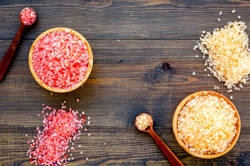 Colorful bath salt on dark wooden background top view copy space