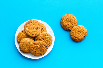 Homemade oatmeal cookies on white plate on blue background top view copy space