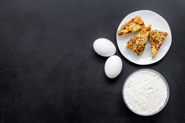 Ingredients for homemade cookies. Fresh cookies near flour, eggs on black background top view space for text
