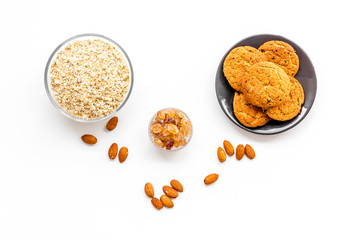 Ingredients for homemade oatmeal cookies. Fresh cookies near foatmeal, nuts and jam on white background top view