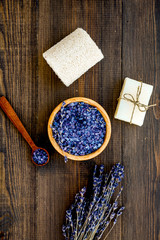 Spa set with lavender spa salt. Purple spa salt near dry lavender branches and washcloth on dark wooden background top view