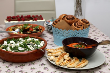 Chicken with roasted pepper sauce, roasted aubergine, feta cheese salad, tapenade bread rolls and tiramisu served on a table. Selective focus. 