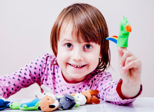 Finger puppet theatre. Cute little child girl playing with animal toys.