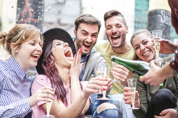 Group of happy friends doing party throwing confetti and drinking champagne outdoor - Young people...