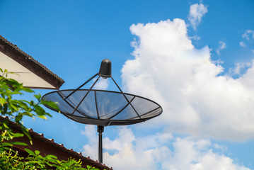 Black Satellite dish on the roof of the house with blue sky 

