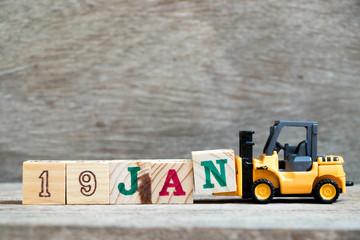 Toy forklift hold block N to complete word 19jan on wood background (Concept for calendar date in 19 month January)