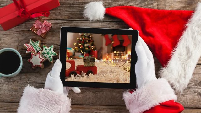 Santa using tablet with Christmas home