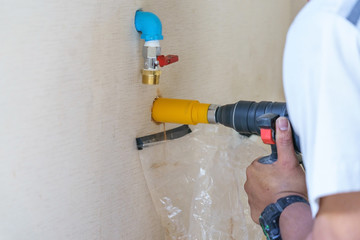 Drills a hole in a concrete wall for an electrical outlet