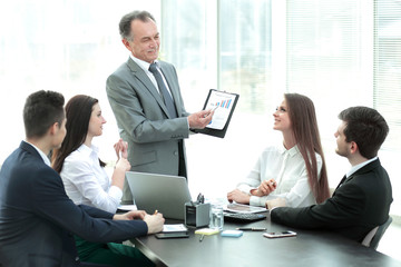 smiling Manager showing a business team ,a graph with financial data.