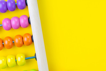 Colorful wooden pink and orange abacus beads on yellow background with copy space for presentation,...