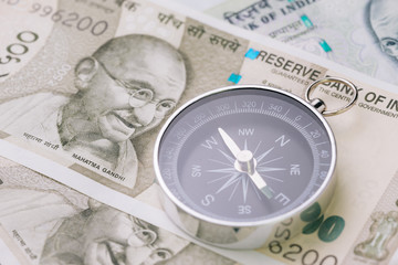 Direction of india financial and economy, new asia developing and emerging market high growth country concept, closed up of compass on indian rupee banknotes on table
