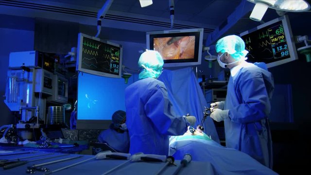 Medical Endoscopy instrument with camera video technology being used by surgical training team in scrubs to perform a Laparoscopy operation on a hospital patient 