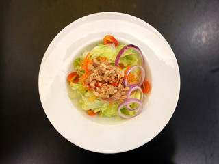 Top view Spicy tuna salad in white dish on the black wooden table. Healthy and smart eating