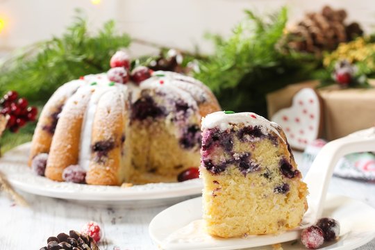 Homemade Blueberry bundt cake and a slice on plate on festive Christmas background