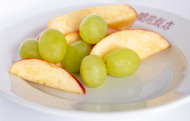 .piece of ripe red apples and grapes close-up on white disk