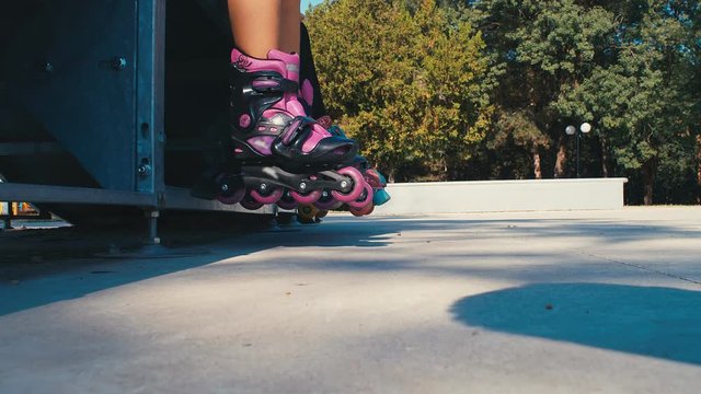 Girls kids legs with roller blades skating in a playground, 4k slow motion