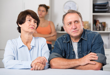 Fototapeta premium Adult daughter is sympathying her sad parens who are sitting at the table