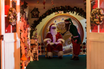 Santa Claus sitting in his armchair and helper elf