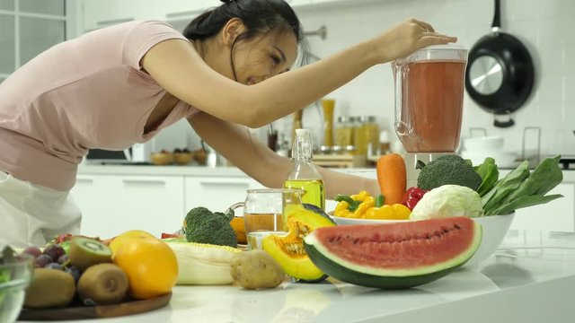 Close up of a woman making fresh juice from vegetables and fruits in kitchen at home.