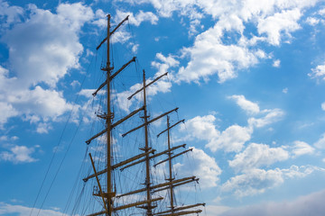 Masts of a sailing vessel against the sky with clouds