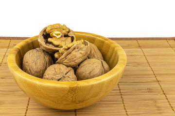 The core and shell of a walnut. A pile of nuts in a bamboo bowl on a rug, isolated on a white background.