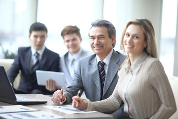 Portrait of mature business man smiling during meeting with colleagues in background