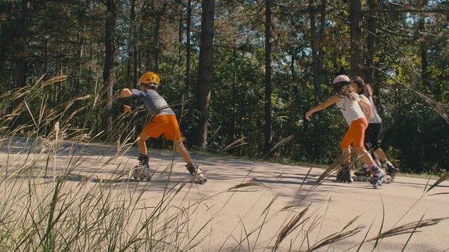 Four kids riding roller blades skating in a row in a playground, 4k slow motion