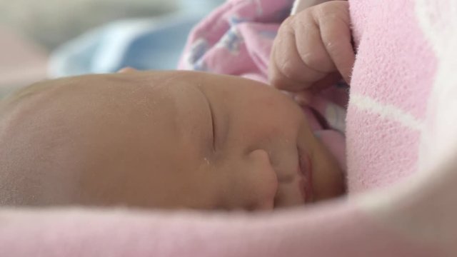Close up shot of a newborn baby girl asleep wrapped in a blanket while in her crib in the hospital