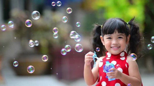 Asian little cute girl or kid blow air soap bubbles with smile. happiness,fun and childhood concept .
